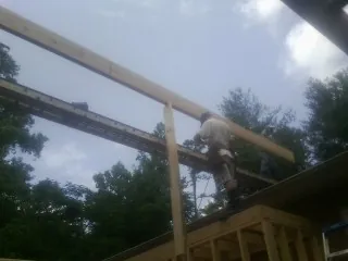 Carpenter setting a ridge beam over a new addition frame — Ice Dam Removal by Roofing Brothers in Lake