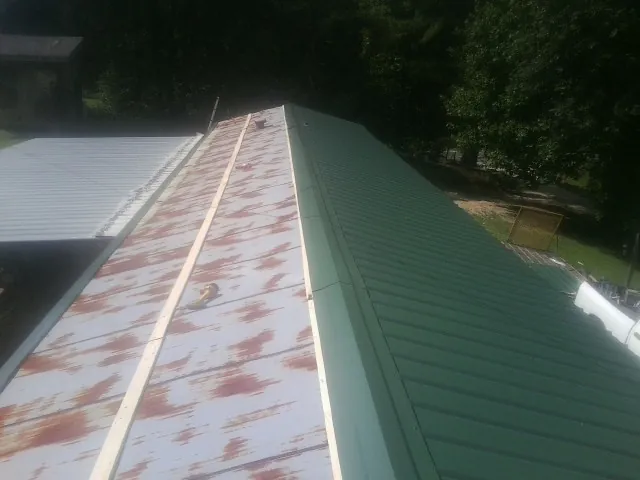 Old rusted panels beside newly installed green metal roofing — Wind Damage Roof Repair by Roofing Brothers in Lake