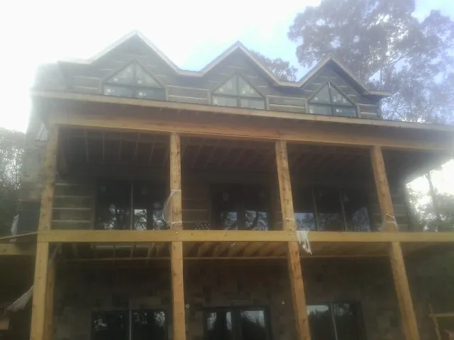Dormers and porch framing on a large log home under construction — Roof Coating work by our crew in Lake