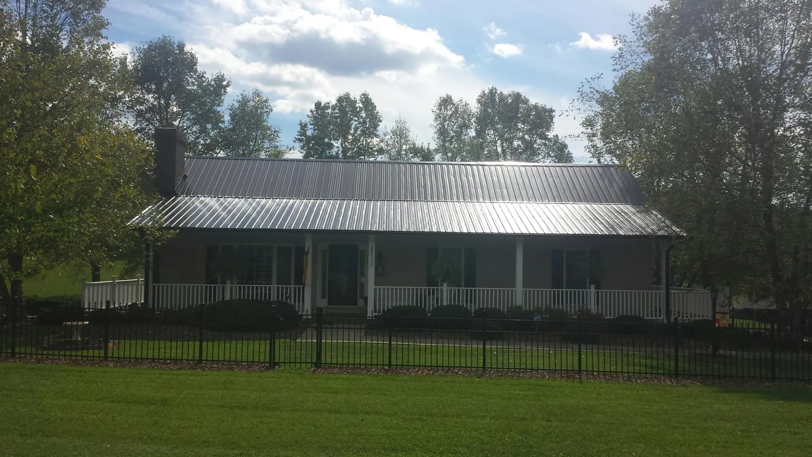 Gray metal roof on a brick ranch with a full width front porch — Gutter Guard Installation work by our crew in Lake